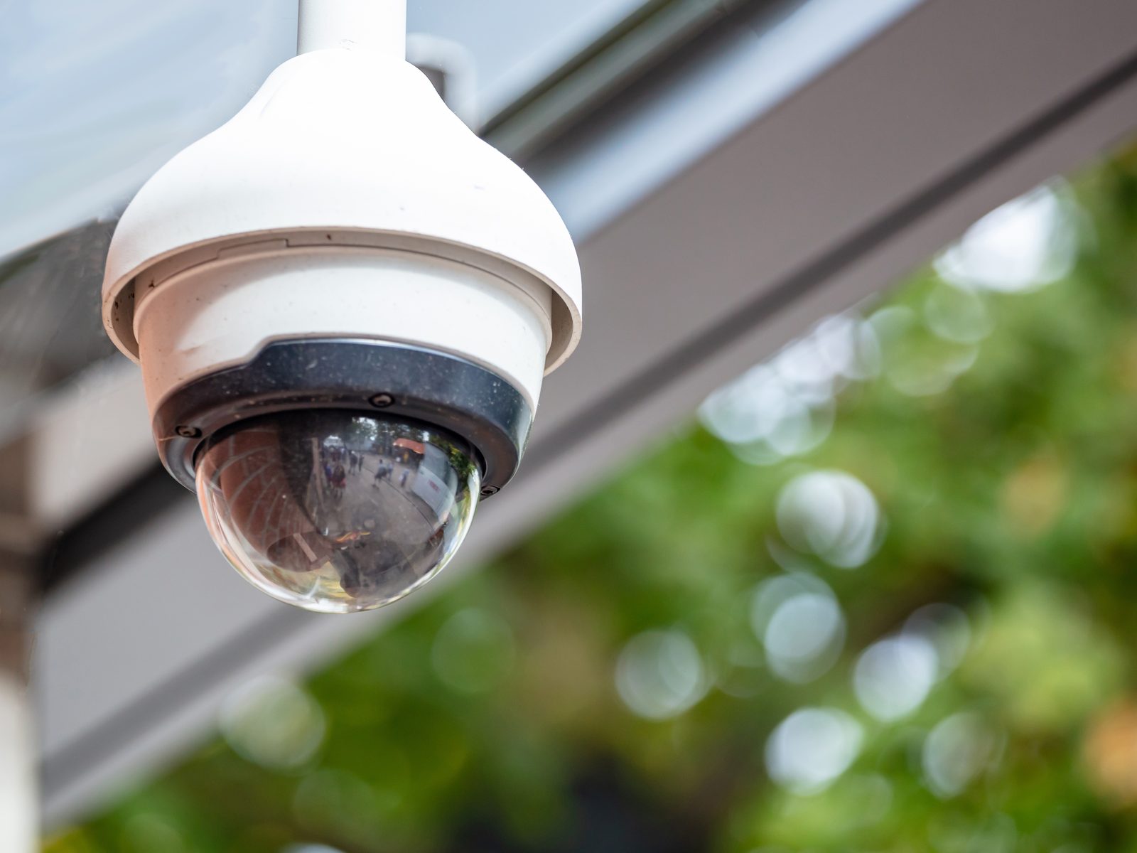 Dome CCTV camera mounted beneath a glass entrance canopy